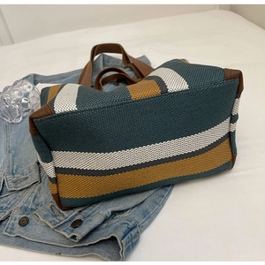 Detailed close-up of striped canvas tote bag with woven texture and leather reinforced edges