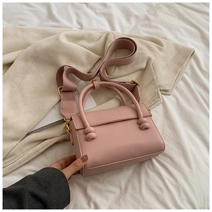 Vue détaillée du cuir grainé et de la bandoulière large sur un sac rose poudré