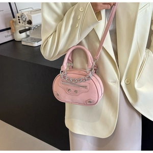 Detailed view of pink mini round handbag with rivets, silver chains and texture
