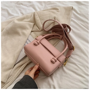 Gros plan d'un petit sac rose texture litchi avec nœuds décoratifs et bandoulière large
