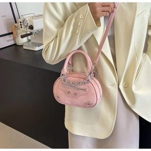 Detail of pink mini handbag with silver rivets and metal chain on a beige blazer