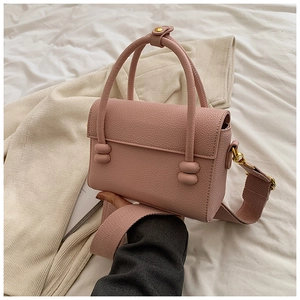 Détail du sac à main en cuir rose avec bandoulière tissée large et finitions dorées