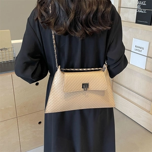 Beige gesteppte Umhängetasche mit Kettenträger und Metalldrehverschluss am Modell