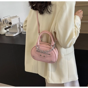Detail view of pink leather crossbody bag with silver rivets and metallic chain strap