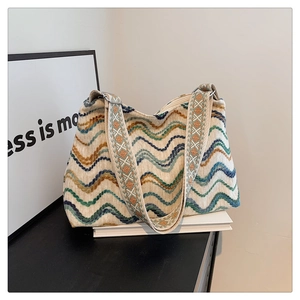 Gros plan du sac seau en tricot bohème avec motifs à vagues colorées et bandoulière brodée