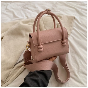 Détail du petit sac carré rose avec texture litchi et large bandoulière en toile