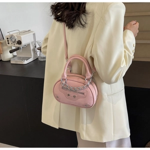 Detail view of pink leather handbag with silver chain and stud rivets worn by a model