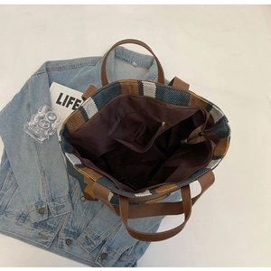 Top-down view of woven striped tote bag interior with zipper pocket and leather straps