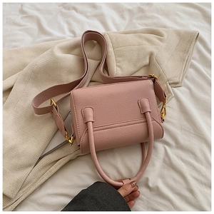 Détail du sac à main en cuir rose avec bandoulière large et finitions dorées