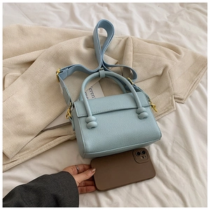 Détail du sac bleu clair en cuir grainé avec bandoulière large et téléphone de taille