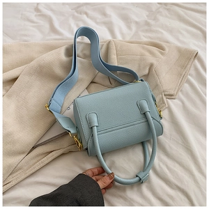 Détail du sac à main bleu clair en cuir grainé avec boucles dorées et bandoulière large
