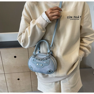Detailed view of light blue leather mini bag featuring silver chain and stud accents