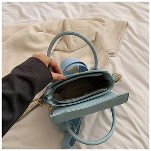 Vue macro du sac en cuir bleu clair avec large bandoulière tissée et zip doré élégant