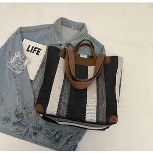 Detailed top view of large striped knit tote bag on denim and white lifestyle props