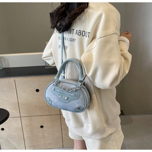 Detail of light blue crossbody bag with silver chains and metallic rivets on model