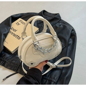 Detail of cream white round crossbody bag with silver chains and studs on leather