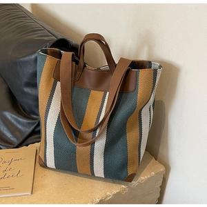 Detail of canvas tote bag with contrast vertical stripes and brown leather handles