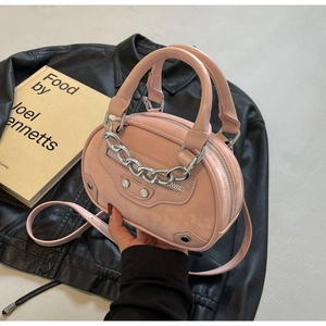 Detailed view of pink semi-oval mini handbag with silver chain on black leather background