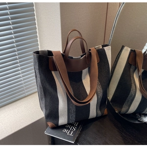Detail of striped canvas tote bag with brown leather handles and rich fabric texture