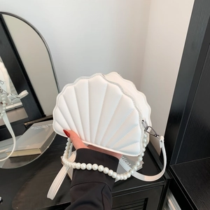 Detail view of a white shell handbag featuring wave quilting and a large pearl handle