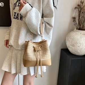 Détail du sac seau en paille tressée avec bordure en cuir beige et cordon