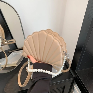 Detail of beige shell-shaped crossbody bag with quilted PU leather and pearl chain strap