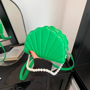 Close-up of green shell-shaped PU bag featuring a pearl chain and metallic zipper detail