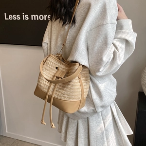 Détail du sac seau en paille tissée avec garniture en cuir marron et cordon