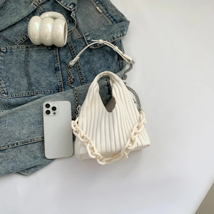 Detail of white pleated PU leather handbag with decorative yellow chain and metal strap