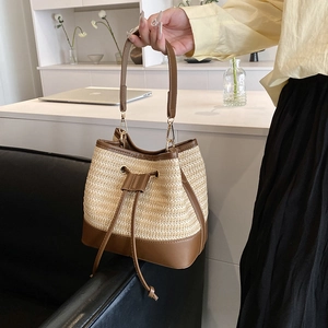 Vue détaillée du sac seau en paille avec cordon en cuir marron et boucles dorées