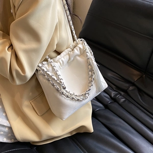 Detail einer weißen Falten-Beuteltasche mit silberner Kette und langen Quasten-Anhängern