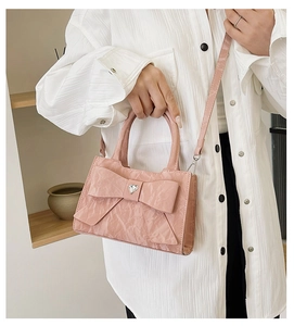 Detailed shot of pink crossbody bag with pleated texture, bow, and heart rhinestone