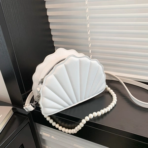Close-up of white shell-shaped PU leather bag with pearl chain and crossbody strap
