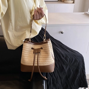 Détail du sac seau en paille tressée avec bordure en cuir marron et cordon serrage