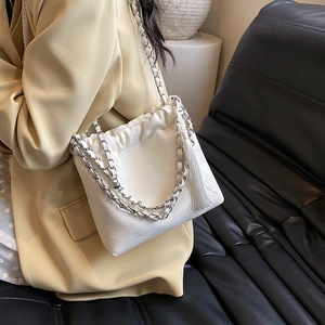Weiße Beuteltasche mit silberner Kette und Quasten-Detail am Modell getragen