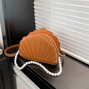 Detail of shell-shaped crossbody bag featuring premium brown leather and pearl strap decor
