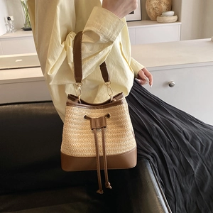 Détail du sac seau en paille tressée avec bordure en cuir marron et cordon de serrage