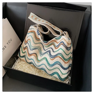 Détail d'un sac seau en laine bohème aux motifs ondulés colorés dans un coffret cadeau
