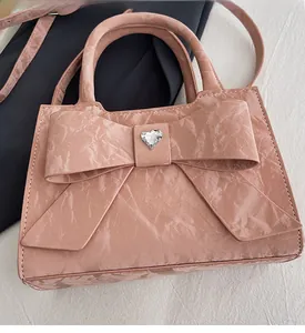 Close-up of pink crinkled patent leather handbag with bow and heart rhinestone