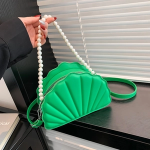 Detail of shell-shaped green bag with faux pearl handle and stitched leather texture