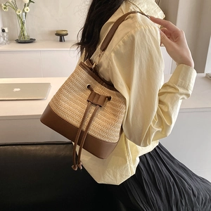 Détail du sac seau en paille tissée avec cordon et bandoulière en cuir marron foncé
