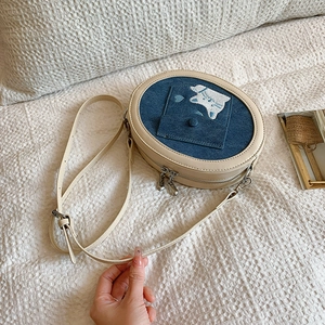 Close-up of cat embroidery and denim fabric on the small oval chain crossbody bag