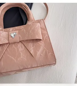Close-up of pink ribbon handbag with heart-shaped crystal on glossy leather