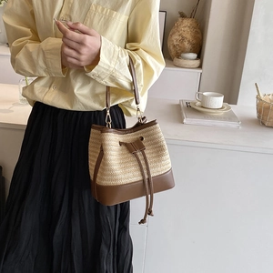 Détail du sac seau en paille avec garniture en cuir marron et fermeture à cordon