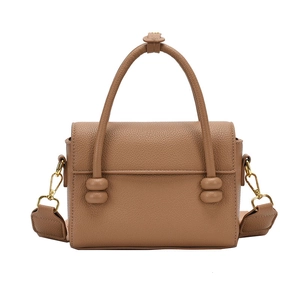 Sac à main en cuir texturé marron avec ferrures dorées et large bandoulière sur fond blanc