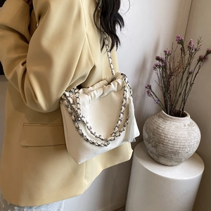 Detail der cremefarbenen Cloud-Tasche mit silberner Kette und Quaste am Modell