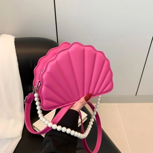 Detailed view of pink shell-shaped crossbody bag with pearl handle and leather strap
