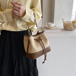 Vue détaillée de la paille et du cuir marron sur le sac seau avec fermeture à cordon