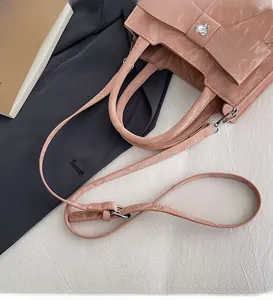 Detail of pink satchel showing textured faux leather, bow decor, and heart rhinestone