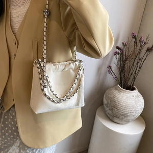 Detailansicht der cremefarbenen Cloud-Tasche mit Kordelzug, Silberkette und Quaste